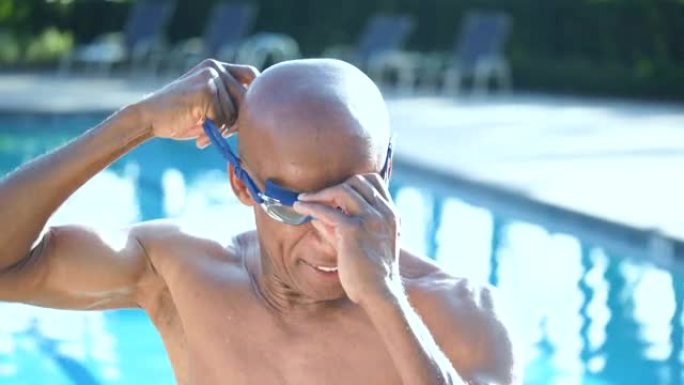 游泳池中的非裔美国人高级男子戴上泳镜