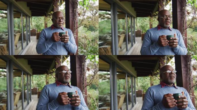 非裔美国高级男子站在阳台上喝咖啡，欣赏美景