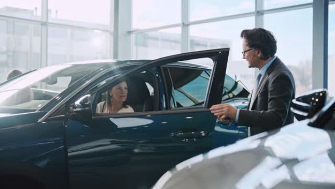 SLO MO成熟男汽车推销员向女顾客展示新车内饰
