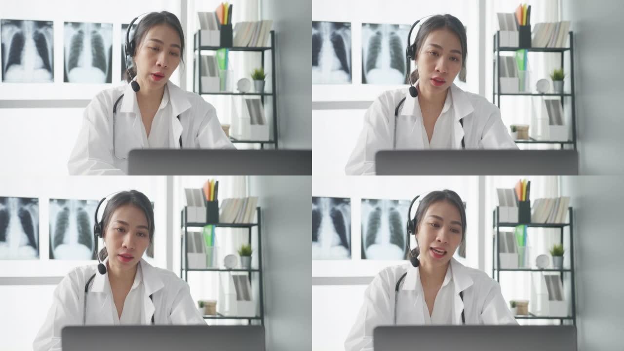 年轻的亚洲女士医生穿着白色医疗制服，配有听诊器，使用电脑笔记本电脑通话视频电话会议，病人在诊所或医院