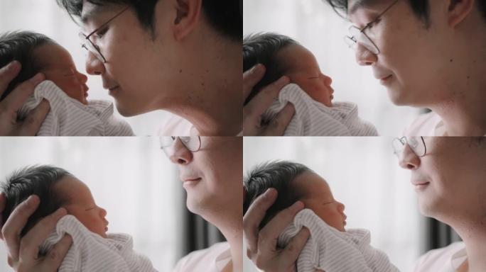 父亲抱着刚出生的儿子，父亲身份。他看着并亲吻他的男孩。