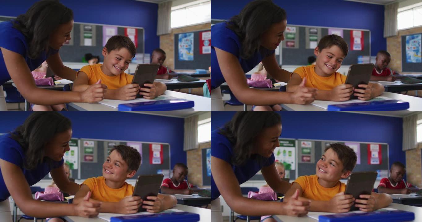 多元化的微笑女教师使用平板电脑帮助坐在教室里的男生