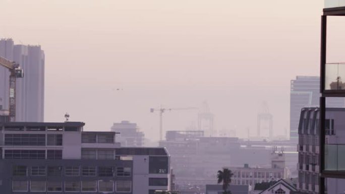 多栋建筑物、建筑工地和造船厂被雾覆盖的城市景观的总体视图