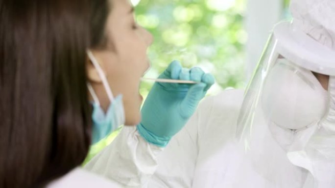 在家新型冠状病毒肺炎标本采集服务。穿着PPE服的医务人员在病人家里用咽拭子取样。家庭医疗服务和新型冠