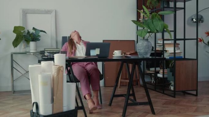 工作场所压力。漂亮的女商人在长时间的笔记本电脑视频通话后感到疲倦，在办公室的桌子上筋疲力尽