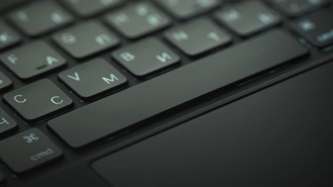 黑色笔记本电脑键盘的特写镜头和一只人手在框架中出现和消失