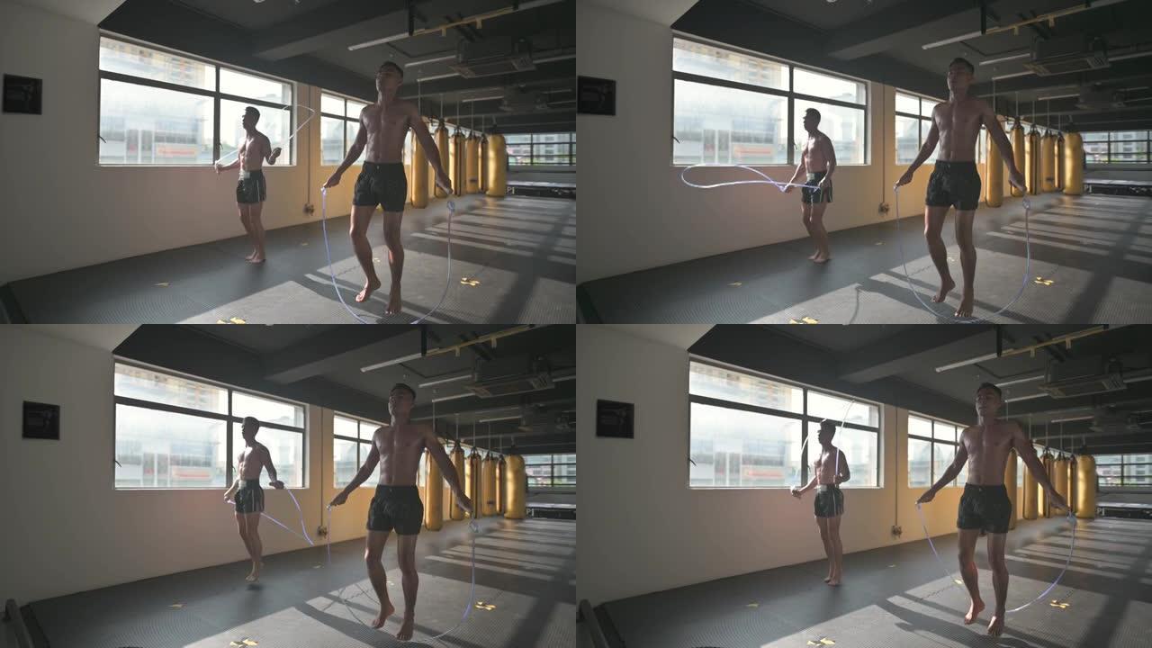 亚洲男运动员跳绳健身俱乐部用一排黄色出气筒沙袋在窗口白天时间