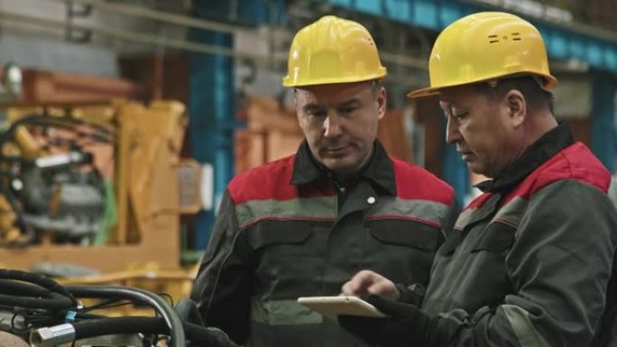 工厂工人与平板电脑在组装车间交谈