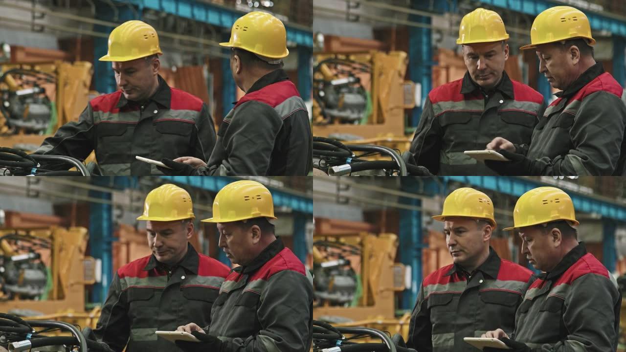 工厂工人与平板电脑在组装车间交谈