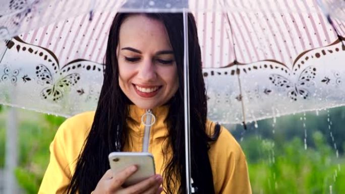 穿着雨衣的SLO MO年轻女子在雨中使用智能手机