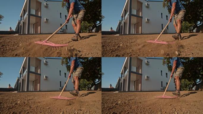 超级SLO MO房主使用耙子将房屋后面草坪上的土壤夷平