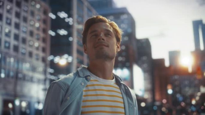 日落时，一个穿着便装的快乐英俊年轻人站在街上的肖像。大城市时尚的男性模特过着城市生活。背景与办公楼和