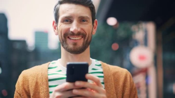 白人男子的肖像使用智能手机，看着相机，在大城市玩得开心。创意男性使用手机App进行电子商务投资，在线