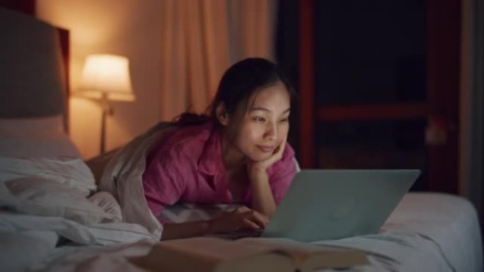 女人在晚上使用笔记本电脑看电影