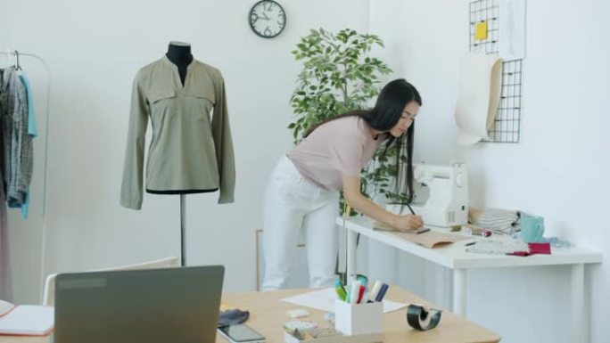 亚洲女裁缝的慢动作在裁缝的假人上测量服装，制作手工服装。