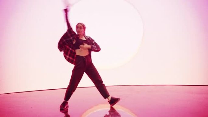 时尚的年轻专业女舞者在工作室环境中的虚拟制作过程中，在带有VFX动画的大Led墙壁屏幕前表演嘻哈舞蹈