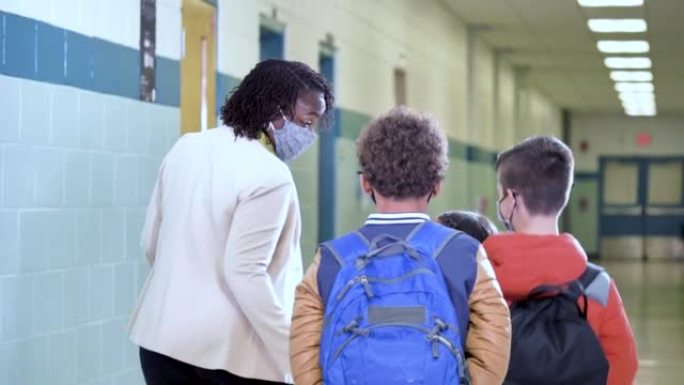 老师和多种族学生走在学校走廊上