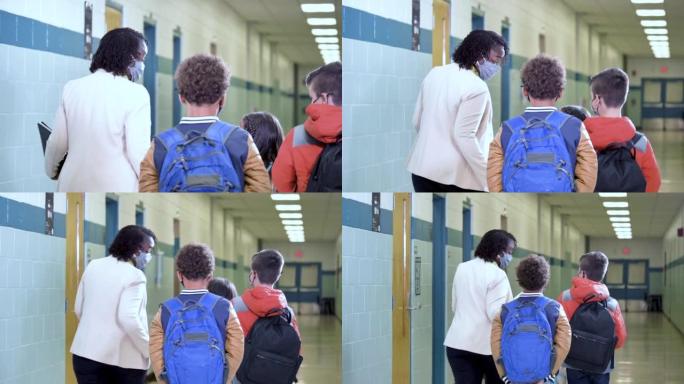 老师和多种族学生走在学校走廊上