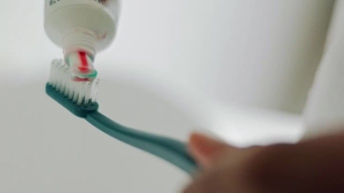 牙刷上的牙膏手，早上的口腔卫生和清洁牙齿，健康和牙齿保健在家里的浴室。放大口腔清洁、美容和健康自我护