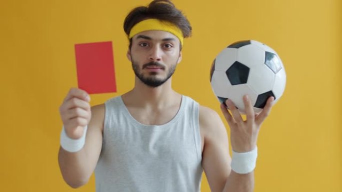 有吸引力的阿拉伯人拿着足球展示红牌的慢动作肖像