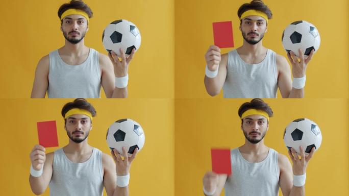 有吸引力的阿拉伯人拿着足球展示红牌的慢动作肖像