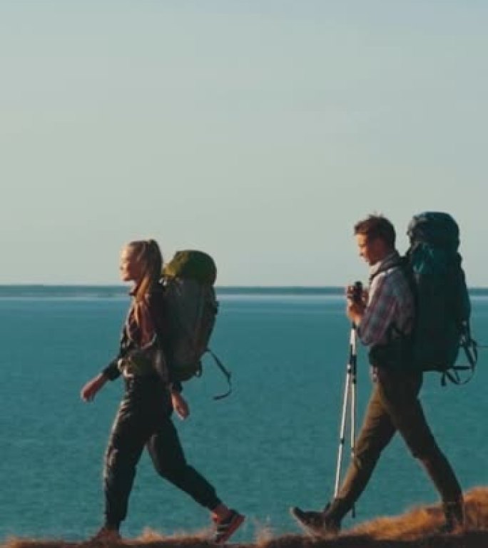 三个登山者在海边的山上行走。慢动作