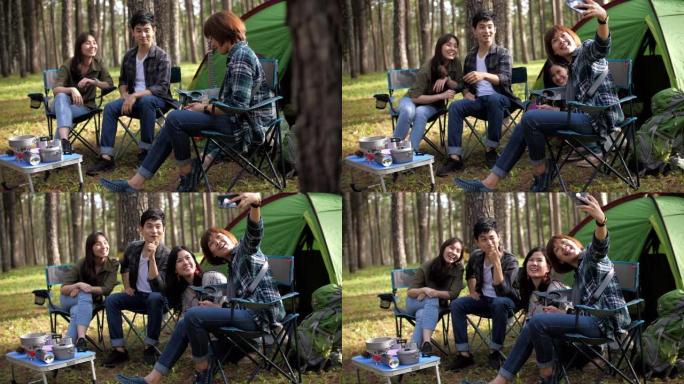 一群朋友在露营地放松和露营，用智能手机自拍有趣