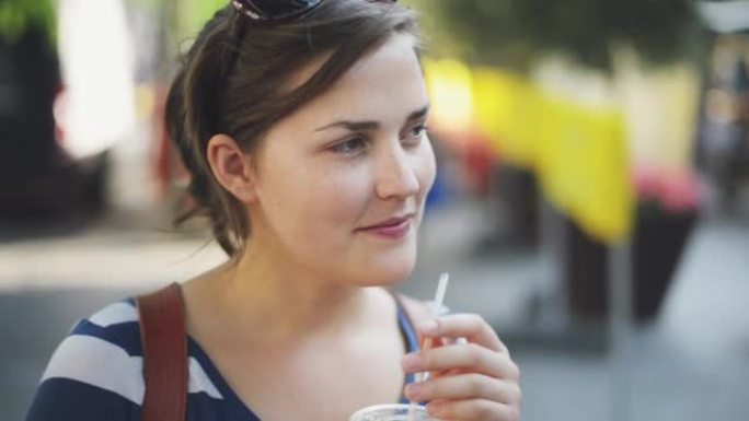 4k视频片段，一名年轻女子在城市外出时享受橙汁
