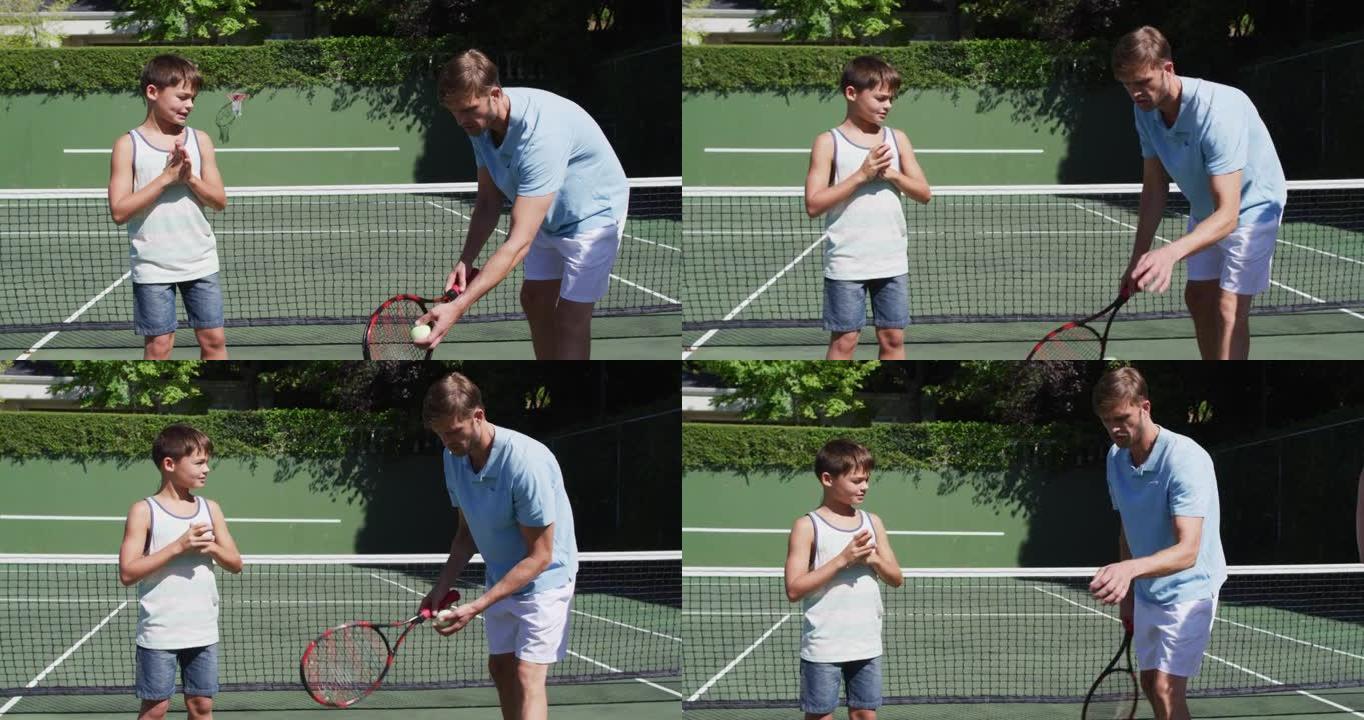 白种人父亲在晴朗的晴天教儿子在网球场打网球