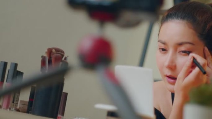 特写亚洲女性影响者教学如何在家使用眼线笔在线教程化妆。