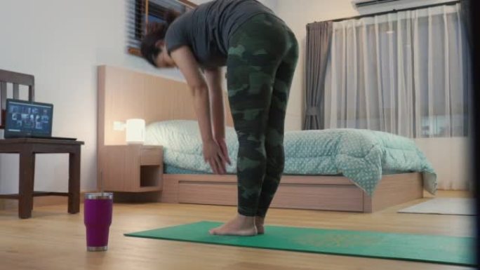 亚洲瑜伽教练训练学生在家卧室伸展运动