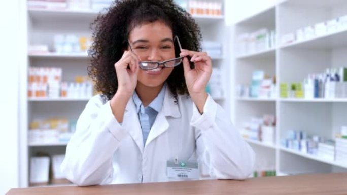 一位年轻的药剂师摘下眼镜并对她的新镜片充满信心的肖像。快乐的非洲化学家或制药工人站在药房处方药柜台后