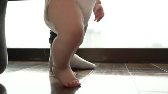 婴儿正在学习学习走路。在他的房子里，父亲和母亲鼓励这是人类学习走路的第一步。家庭中的温暖
