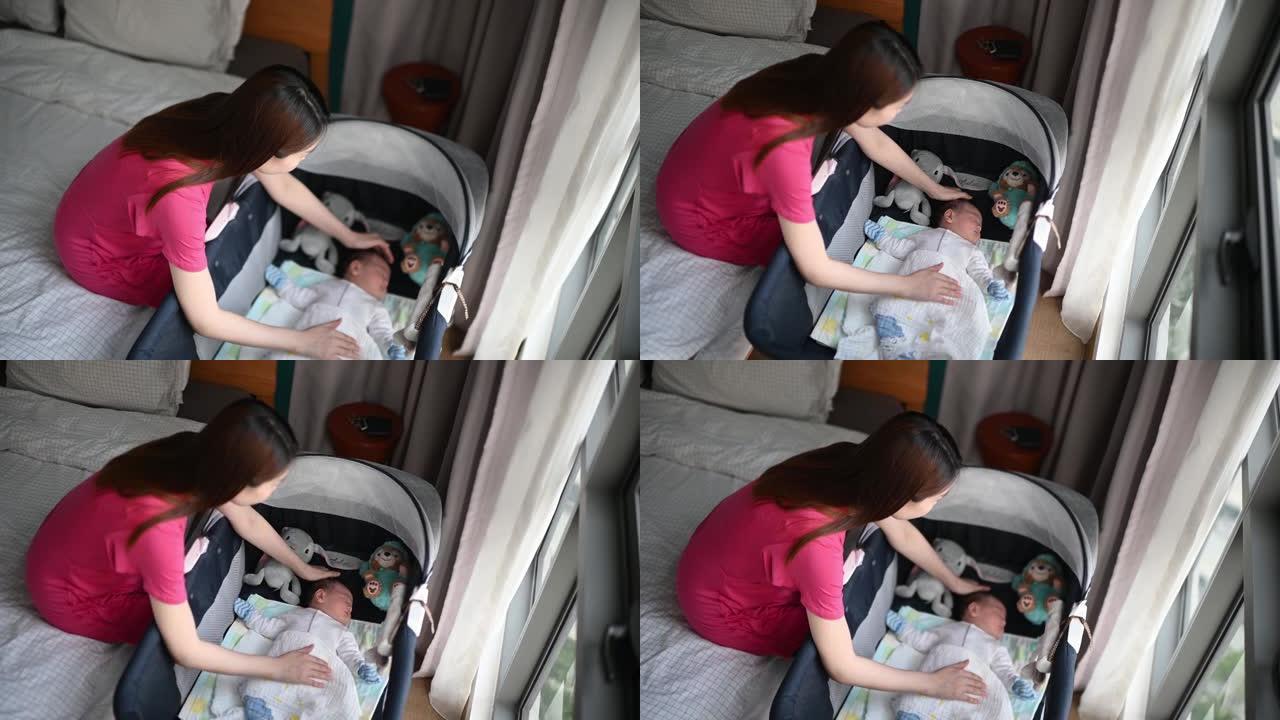 亚洲华裔年轻母亲在卧室的婴儿床中轻拍婴儿男婴