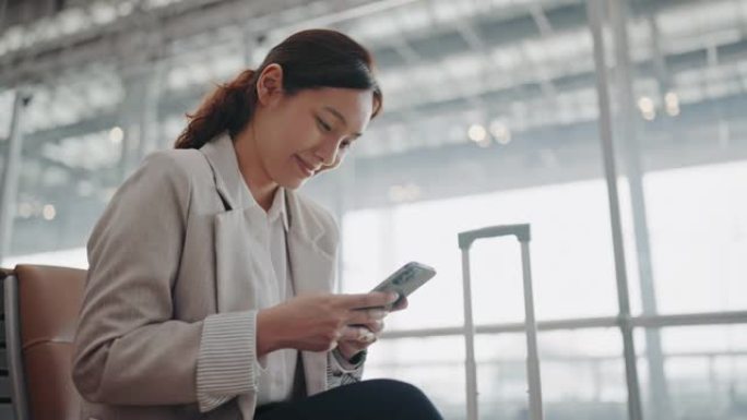 微笑的年轻亚洲妇女在机场使用智能手机