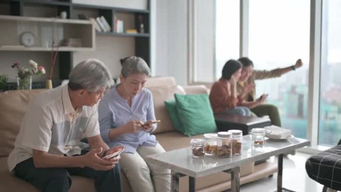 老花眼的亚洲华裔老年夫妇在周末休闲时间难以在客厅学习使用智能手机