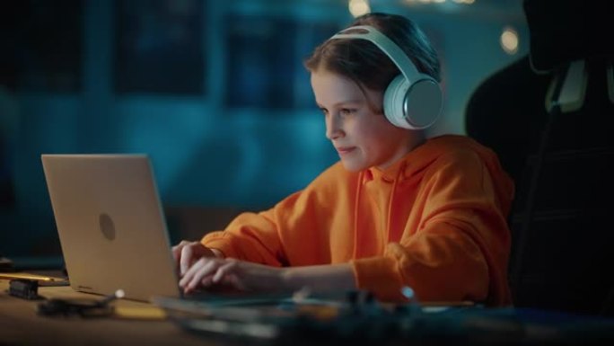 戴着耳机的聪明小男孩在家里黑暗舒适的房间里使用笔记本电脑。快乐的青少年在线浏览教育研究，在社交媒体上