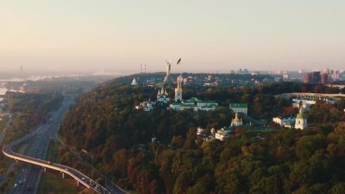 无人机飞向基辅的祖国雕像和巨大的乌克兰国旗，在美丽宁静的夏季日出全景。