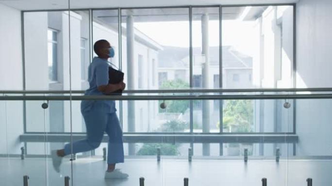 非裔美国女卫生工作者戴着口罩在医院的走廊里奔跑