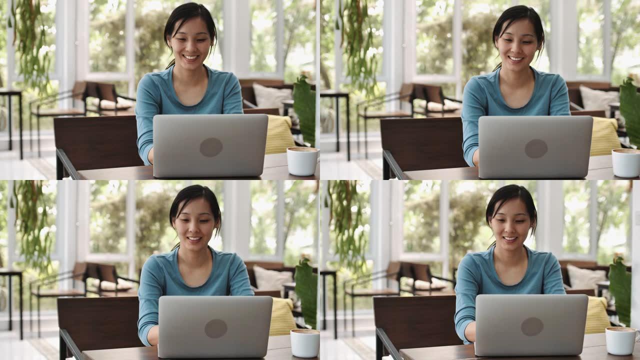 在咖啡馆里用笔记本电脑工作的亚洲妇女