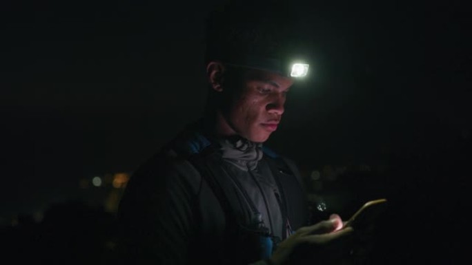 4k视频片段，一名男子戴着头灯，晚上在外面使用手机