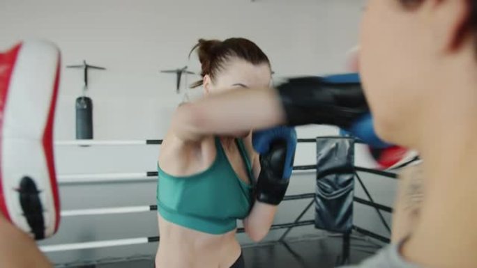 积极进取的年轻女子拳击手训练，女伴在健身房室内打孔