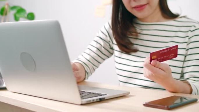 女人手里拿着信用卡在使用笔记本电脑搜索网上商店的特写镜头