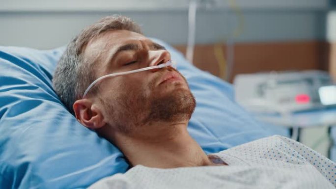 医院病房: 穿着鼻插管睡在床上的英俊年轻人的肖像，生病后完全康复。男病人梦想着自己漫长而幸福的未来生