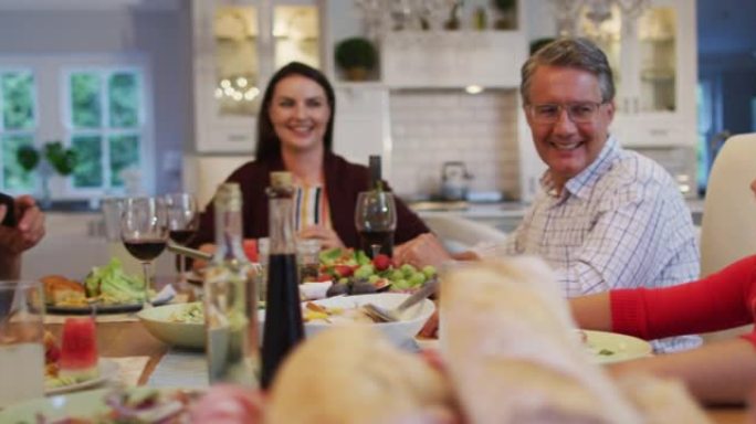 快乐的高加索多代家庭在家庭用餐时在餐桌上玩智能手机