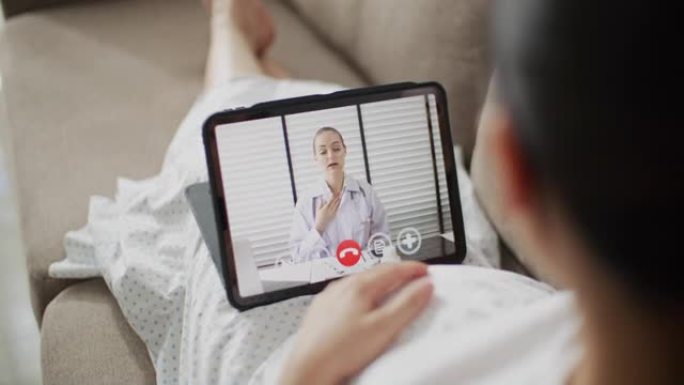 孕妇在家中与数字平板电脑上的医生进行视频通话