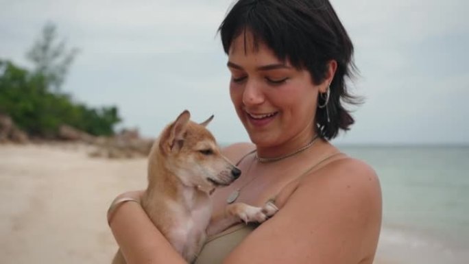 年轻女子在海滩上与狗一起享受