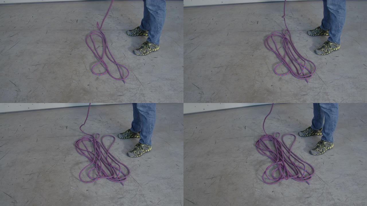 特写: 雄性守望者在帮助登山者下降的同时将绳索放在地面上。