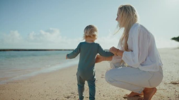 母亲和年幼的婴儿带孩子在沙滩走路