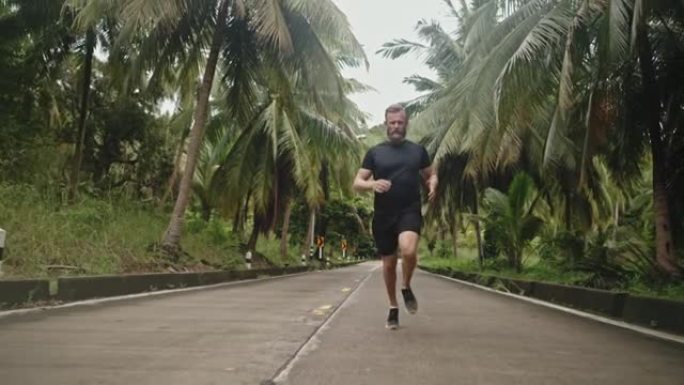 男子在路上奔跑热带风景区林间公路跑步健身